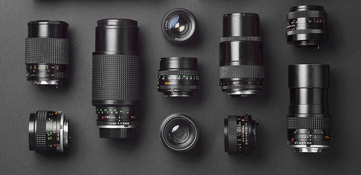 Assorted camera lenses displayed on a dark background.